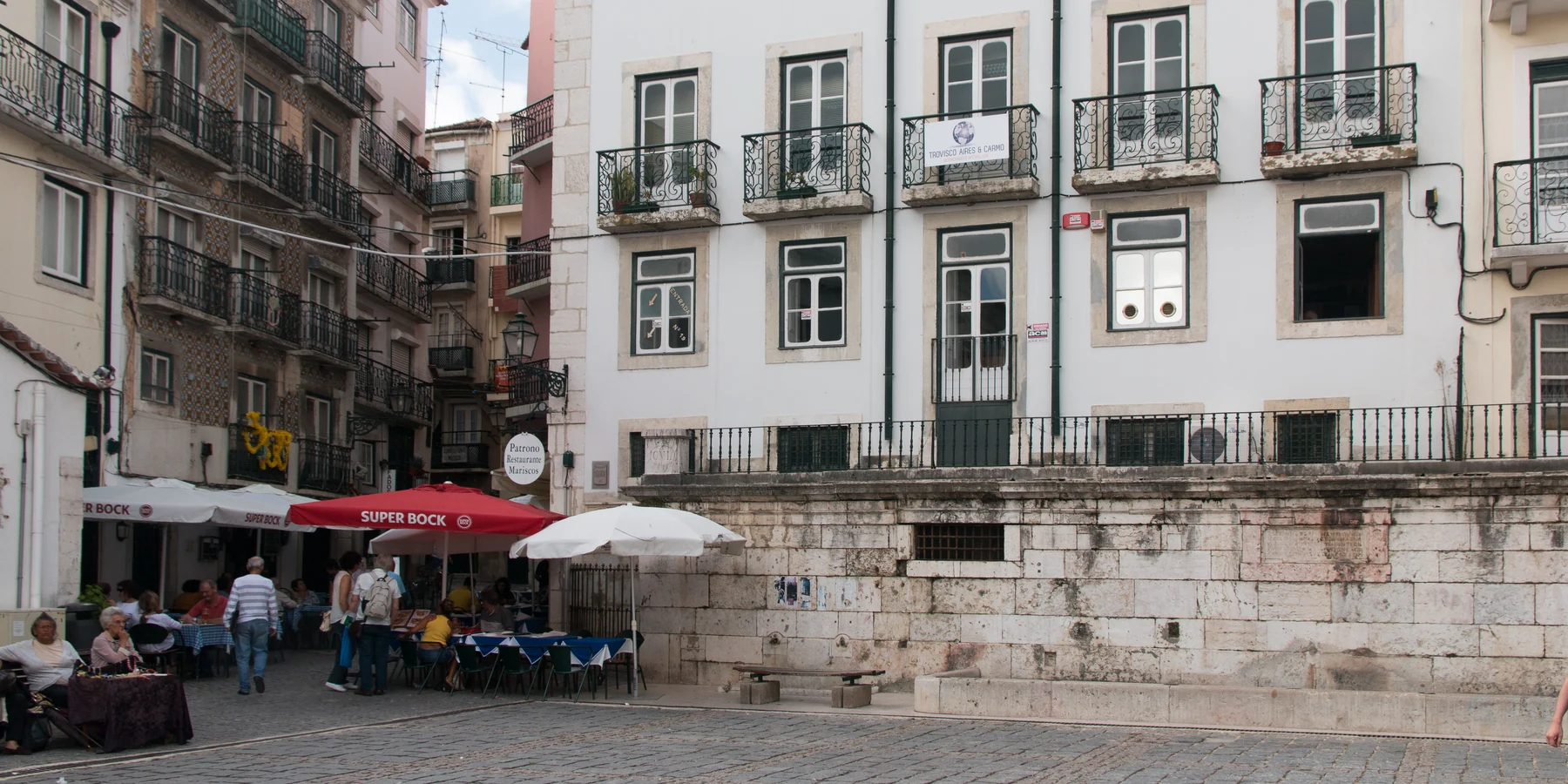Chafariz de Dentro fountain and the surrounding Alfama square, with its stone spouts and basin visible